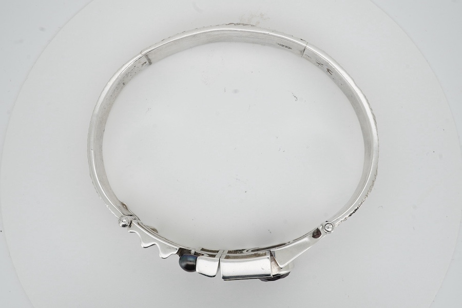 A contemporary silver and amethyst bangle, of abstract, Cubist-inspired design, to a textured band, set with a circular-cut amethyst and a cultured pearl, inner circumference approximately 20.8cm, maker's mark ZC, stampe